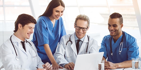 TSGPhysIntPlaybookCoverPhoto_ MedProfTeamChartLaptopSmile _600x300px